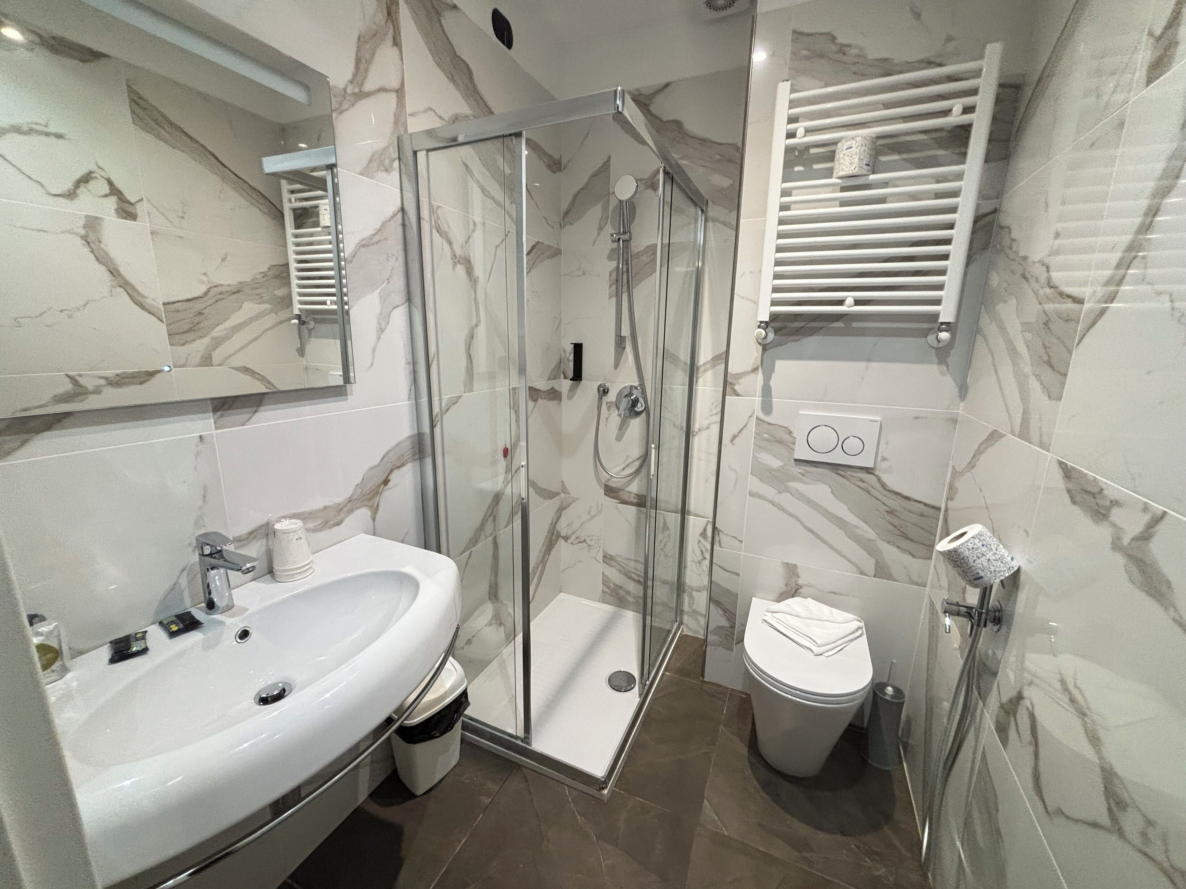 Un baño moderno con ducha acristalada, lavabo blanco y retrete.