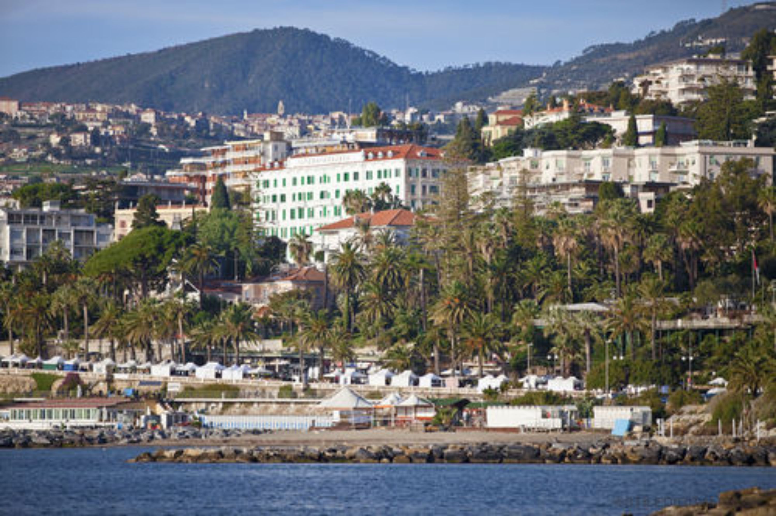 Un paysage urbain côtier avec des bâtiments, des palmiers et une étendue d’eau.