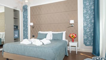 Una cama bien hecha con colcha azul y blanca, una mesita de noche con un florero y una lámpara de pared.
