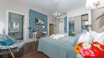 Habitación de hotel con cama, escritorio, silla y baño visible a través de una puerta abierta.