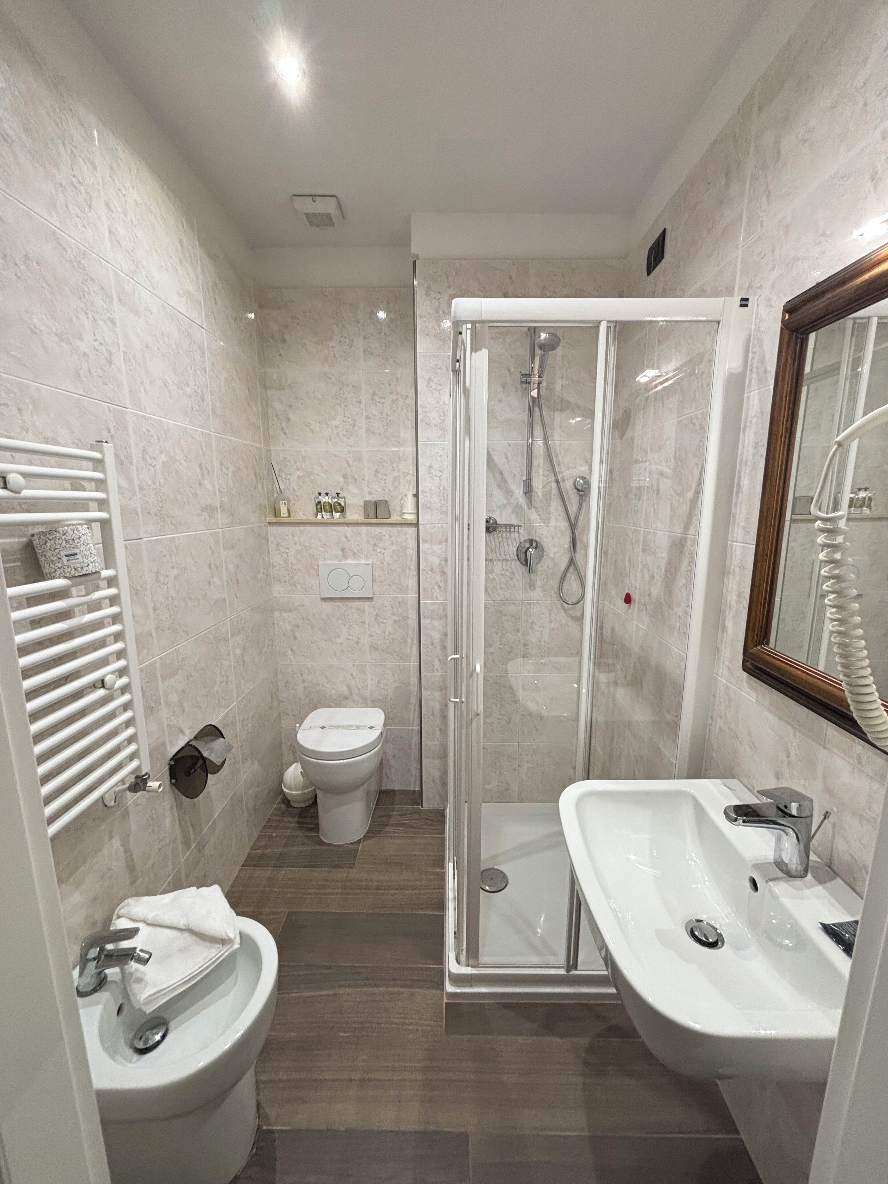 A modern bathroom with a glass-enclosed shower, a white sink, and a toilet.