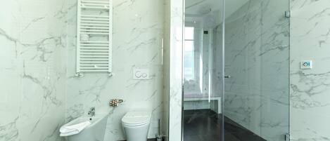 A modern bathroom with a bidet, toilet, and glass-enclosed shower area.