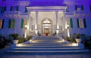A grand entrance with a central staircase leading to a door, flanked by columns and potted plants. - Grand Hotel & des Anglais (Sanremo)