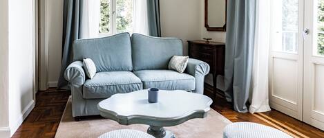 A room with a light blue sofa, a white table, and two ottomans.