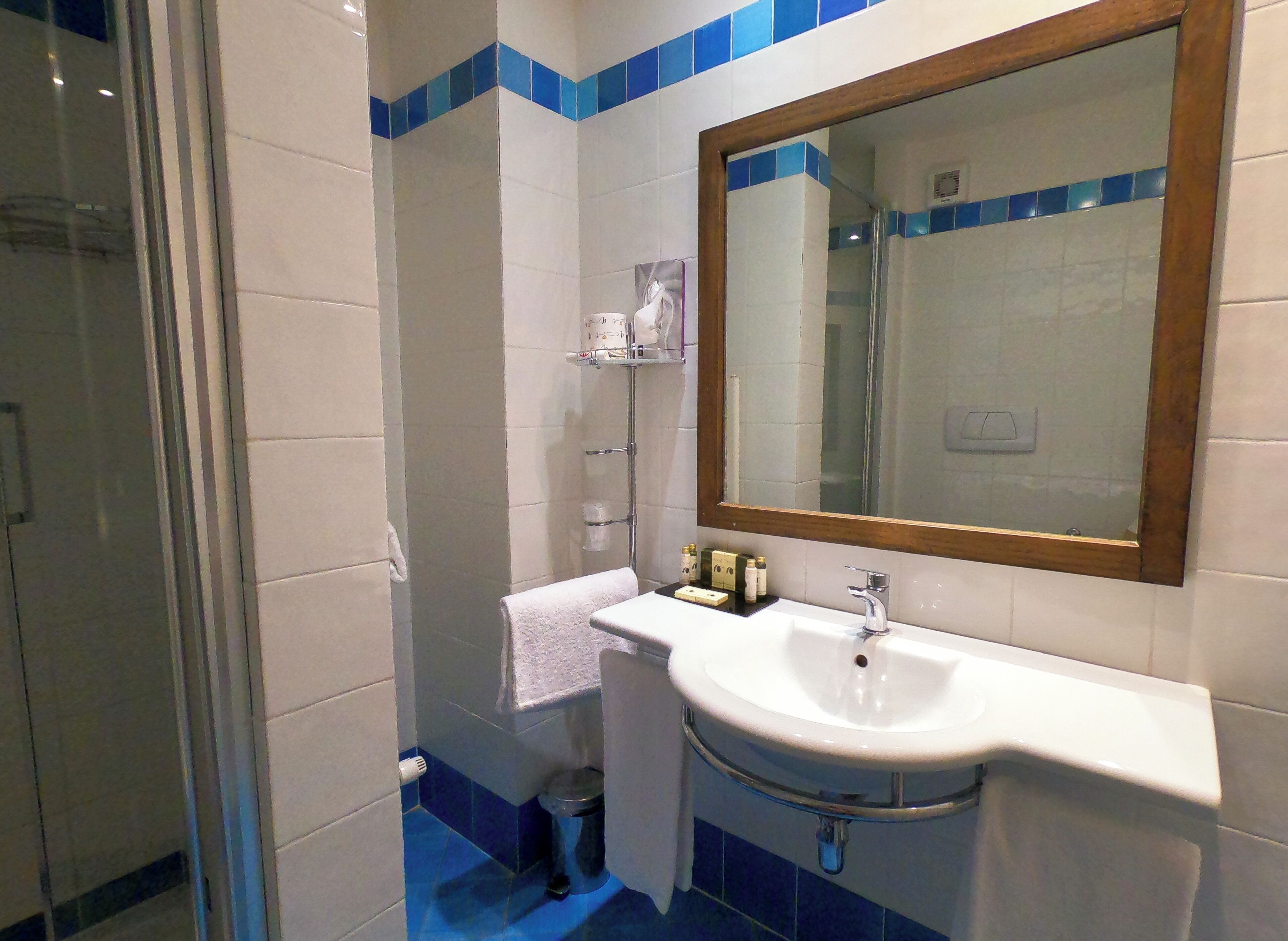Une salle de bain avec un lavabo blanc, un miroir et une douche.
