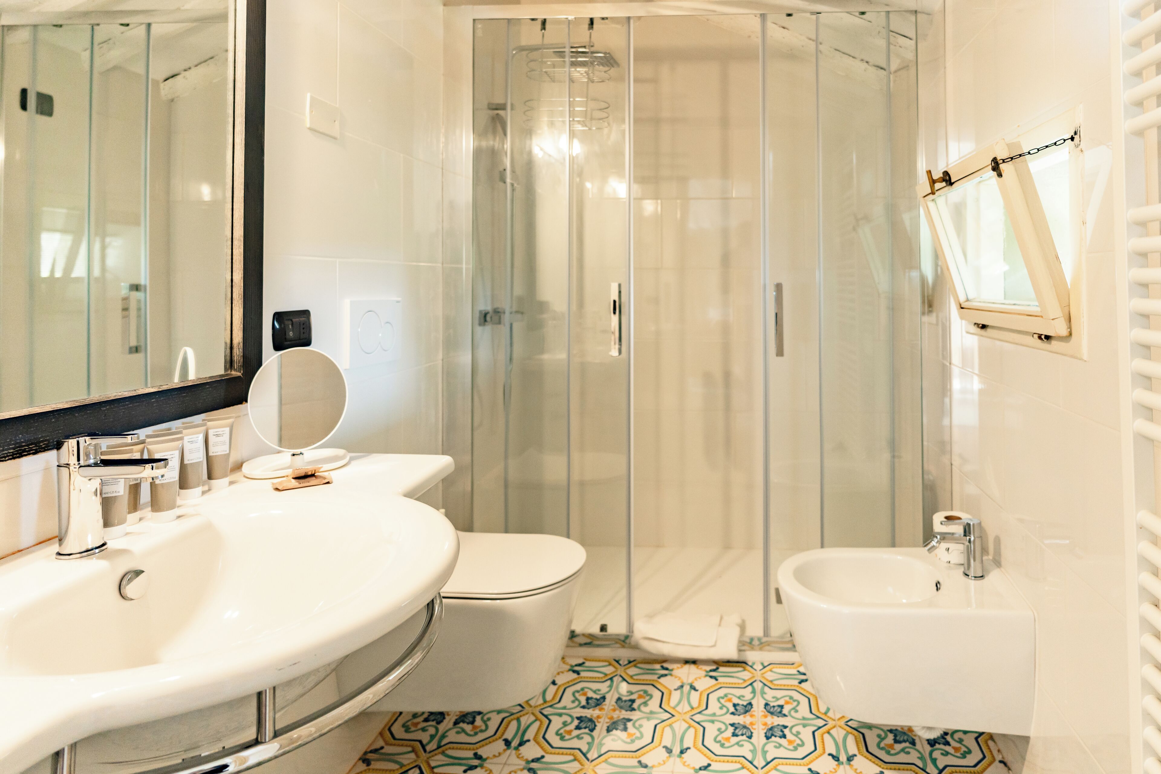 A modern bathroom with a glass-enclosed shower, a large sink, a toilet, and a bidet.