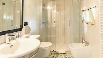 A modern bathroom with a glass-enclosed shower, a large sink, a toilet, and a bidet.