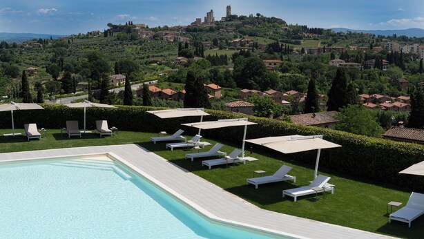 A pool area with lounge chairs and umbrellas, a view of a hilltop town with historic buildings. - Cappuccina Country Resort (San Gimignano)