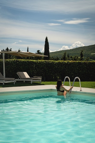 Una piscina al aire libre de temporada, sombrillas