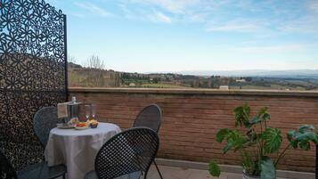 Um terraço com uma mesa posta para dois, uma grade de metal decorativa e um vaso com planta.