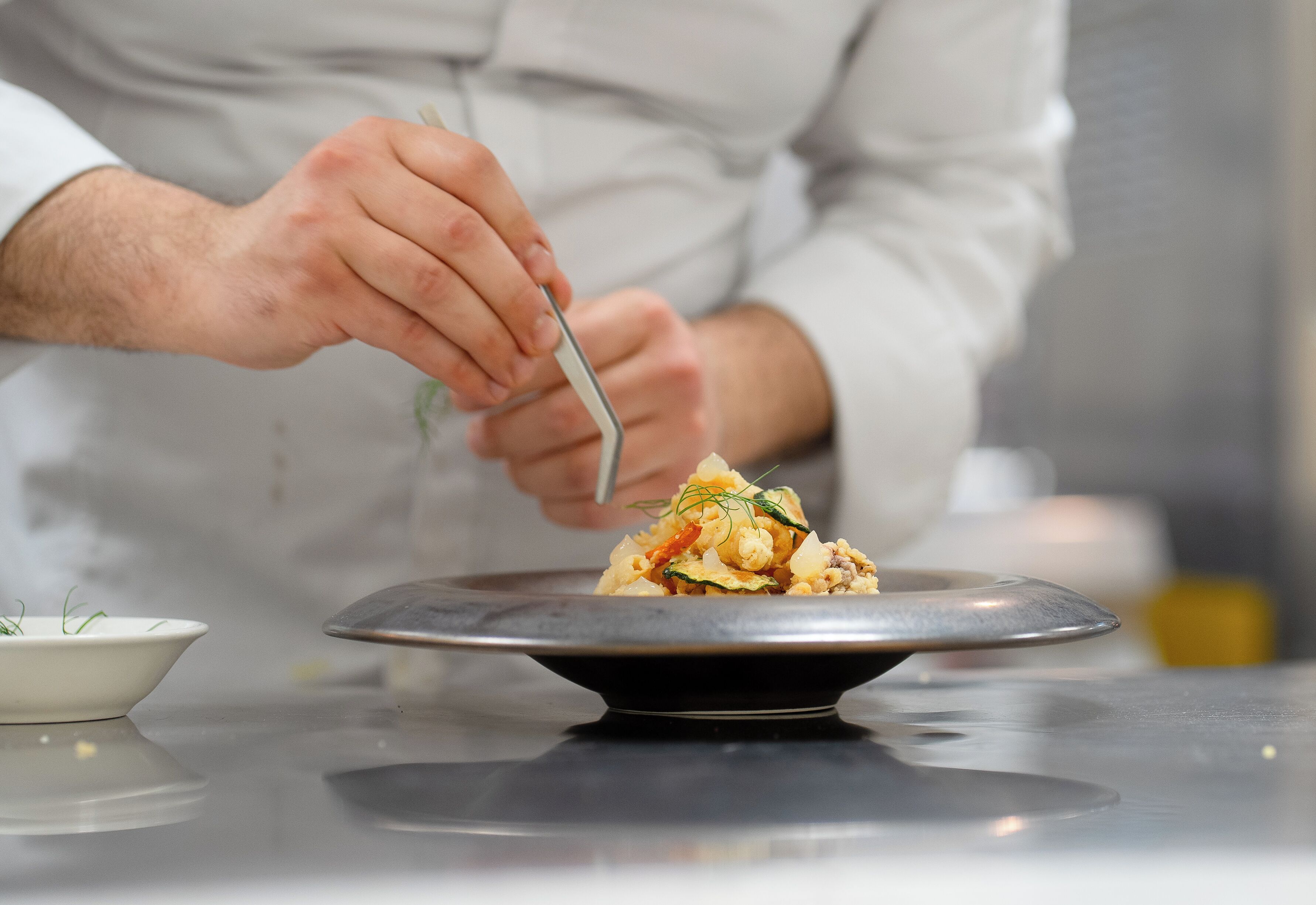 A person serving food from a bowl onto a plate.
