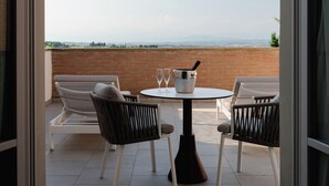 A balcony with a table and chairs, a bucket with glasses, and a view of the landscape. - Cappuccina Country Resort (San Gimignano)