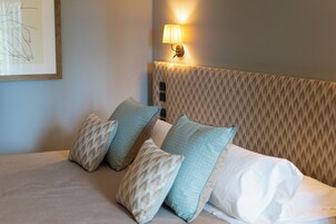 Un letto con cuscini decorati e una testiera dal disegno materico.