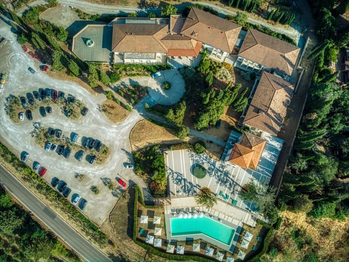 An aerial view of a resort with a swimming pool, multiple buildings, and a parking area.