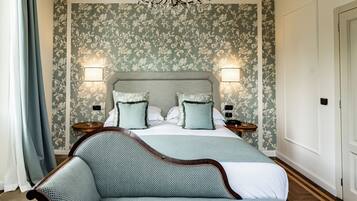 A bedroom with a large bed, two bedside tables, a chandelier, and floral wallpaper.