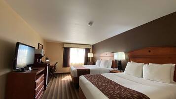 A hotel room with two beds, a desk, a television, and a dresser.
