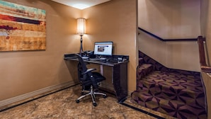 Ein Hotelzimmer mit Schreibtisch, Stuhl, Computer, Lampe und einer gemusterten Treppe.