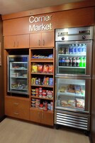 Un mercado de barrio con secciones refrigeradas y estantes repletos de aperitivos y bebidas.