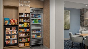 Una tienda de barrio con estantes llenos de aperitivos, bebidas y otros productos alimenticios.
