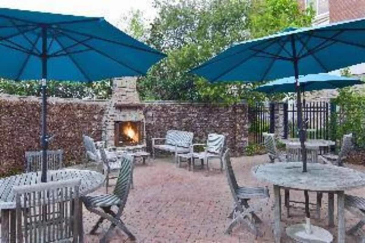 An outdoor patio area with stone walls, a fire pit, and outdoor furniture.
