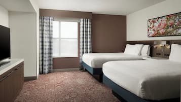 Habitación de hotel con dos camas, un televisor de pantalla plana, un ventanal grande con cortinas estampadas y una obra de arte floral en la pared.