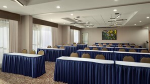 A conference room with multiple tables, chairs, and a large window with curtains.
