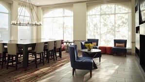A spacious living room with a dining area, large windows, and a chandelier. - Hilton Garden Inn Jackson/Madison (Madison)
