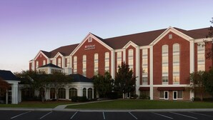 A large brick building with a prominent 'Hilton Garden Inn' sign, featuring a symmetrical facade with large windows and a central entrance.