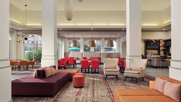 A spacious lobby with high ceilings, multiple seating areas, and a bar. - Hilton Garden Inn Jackson/Madison (Madison)