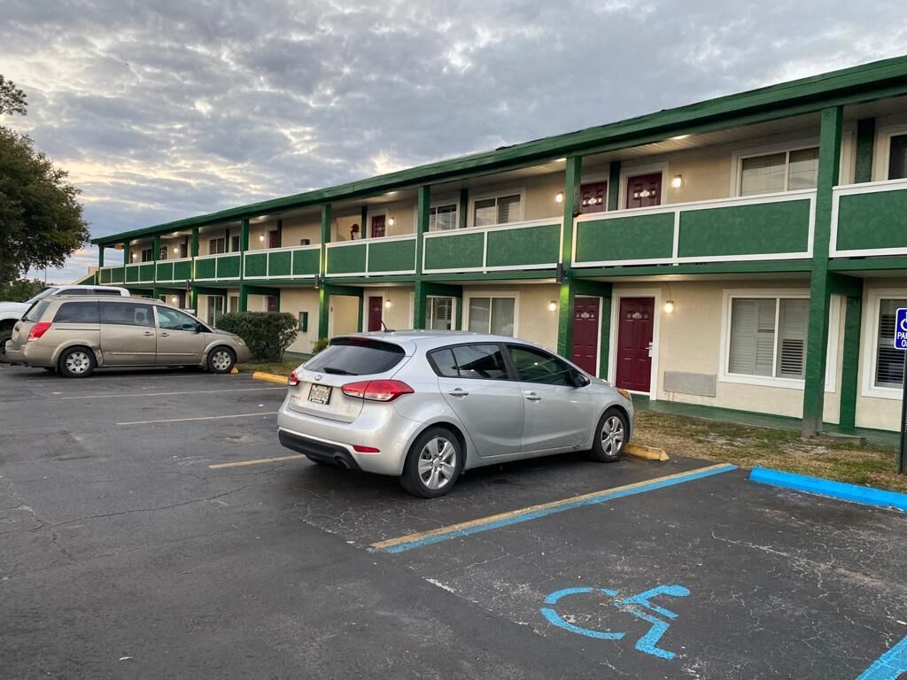 Un motel con estacionamiento, un espacio reservado para discapacitados y un edificio con múltiples ventanas y puertas.