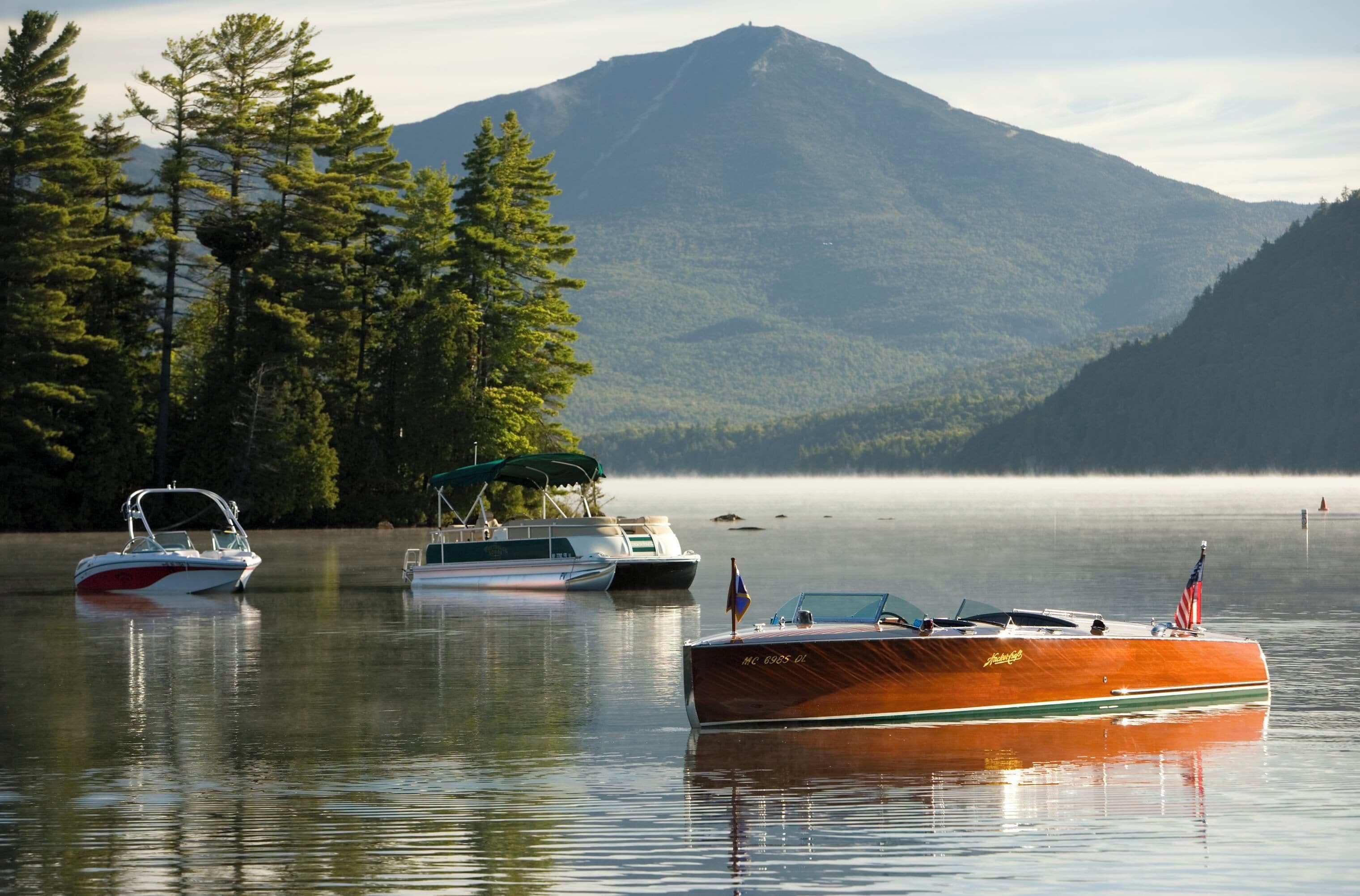 Un lago tranquilo con barcos y una montaña al fondo.