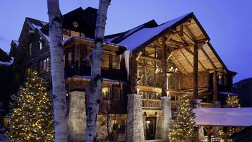 A log cabin with a large porch, stone foundation, and multiple windows.