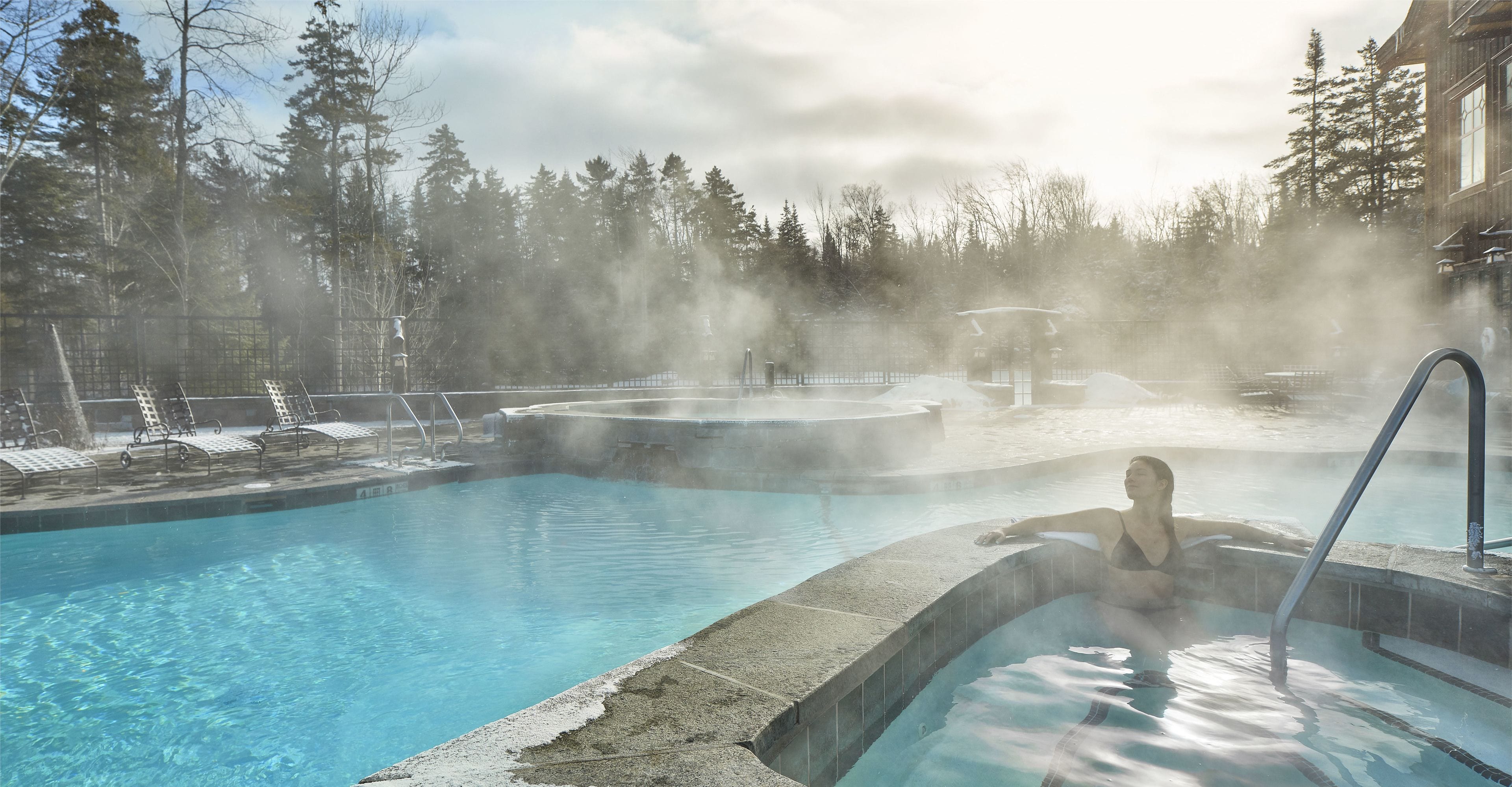 Una piscina techada, una piscina al aire libre, sombrillas
