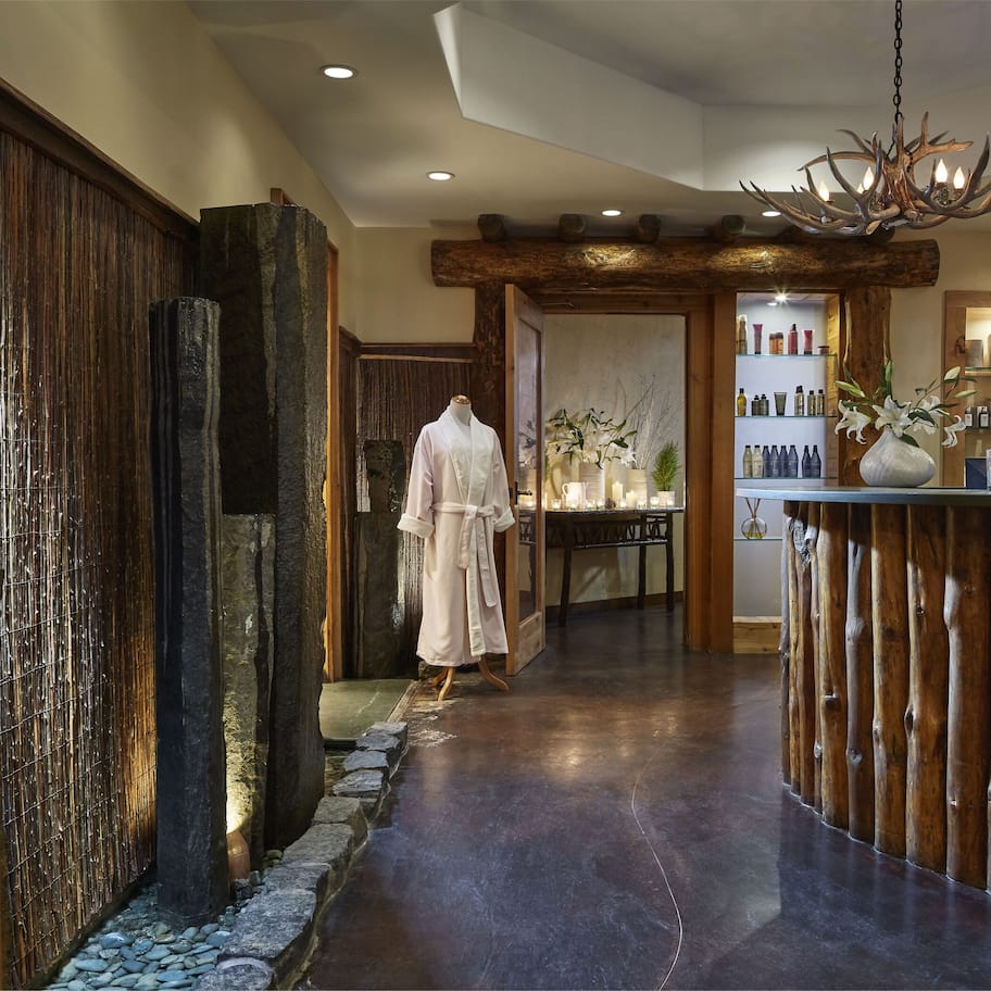 A hotel lobby with a wooden reception desk, a chandelier, and a large painting of a mountain landscape.
