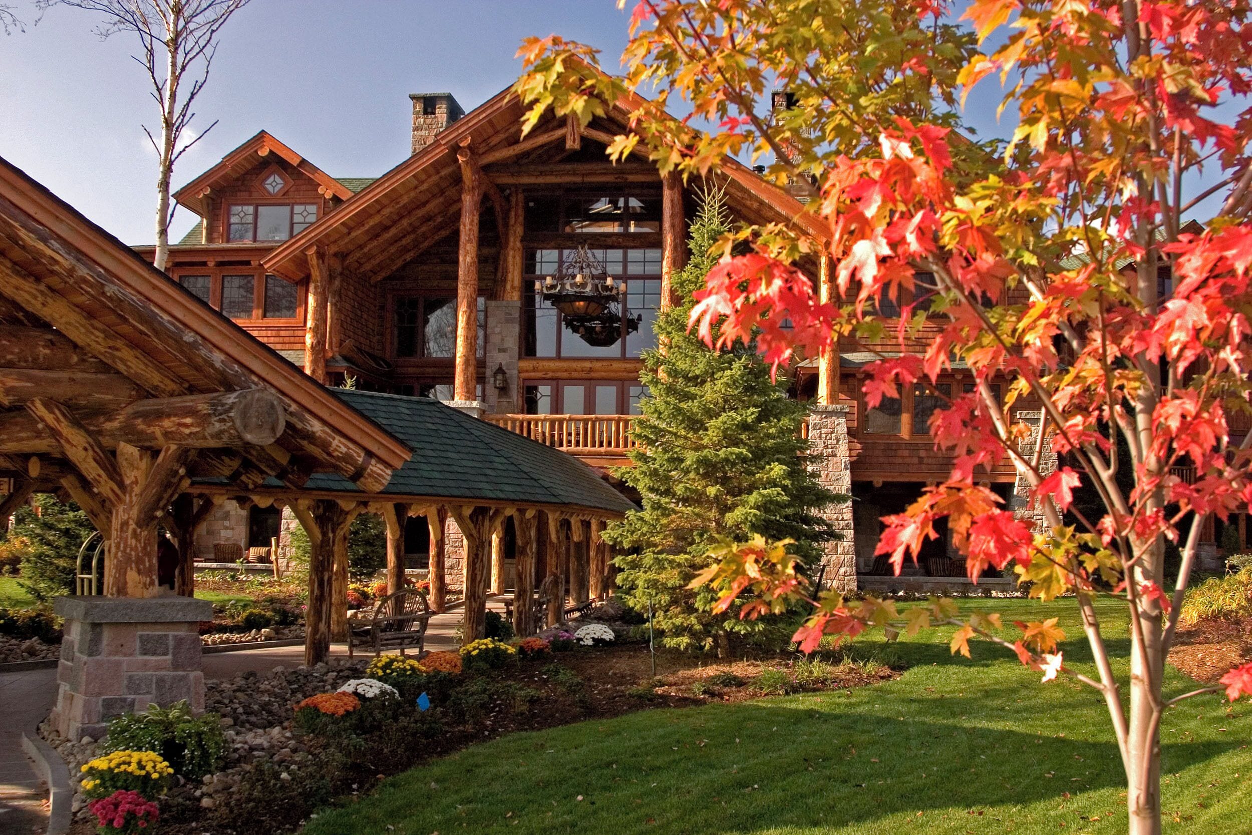A lodge with a covered porch, stone foundation, and a large window.