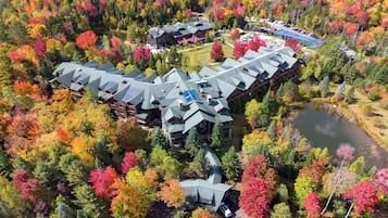 Un albergue con varias construcciones, un aparcamiento y un estanque.
