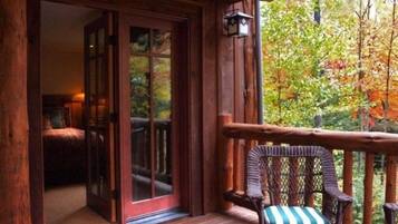 A wooden deck with a wicker chair and a sliding glass door leading to a room.