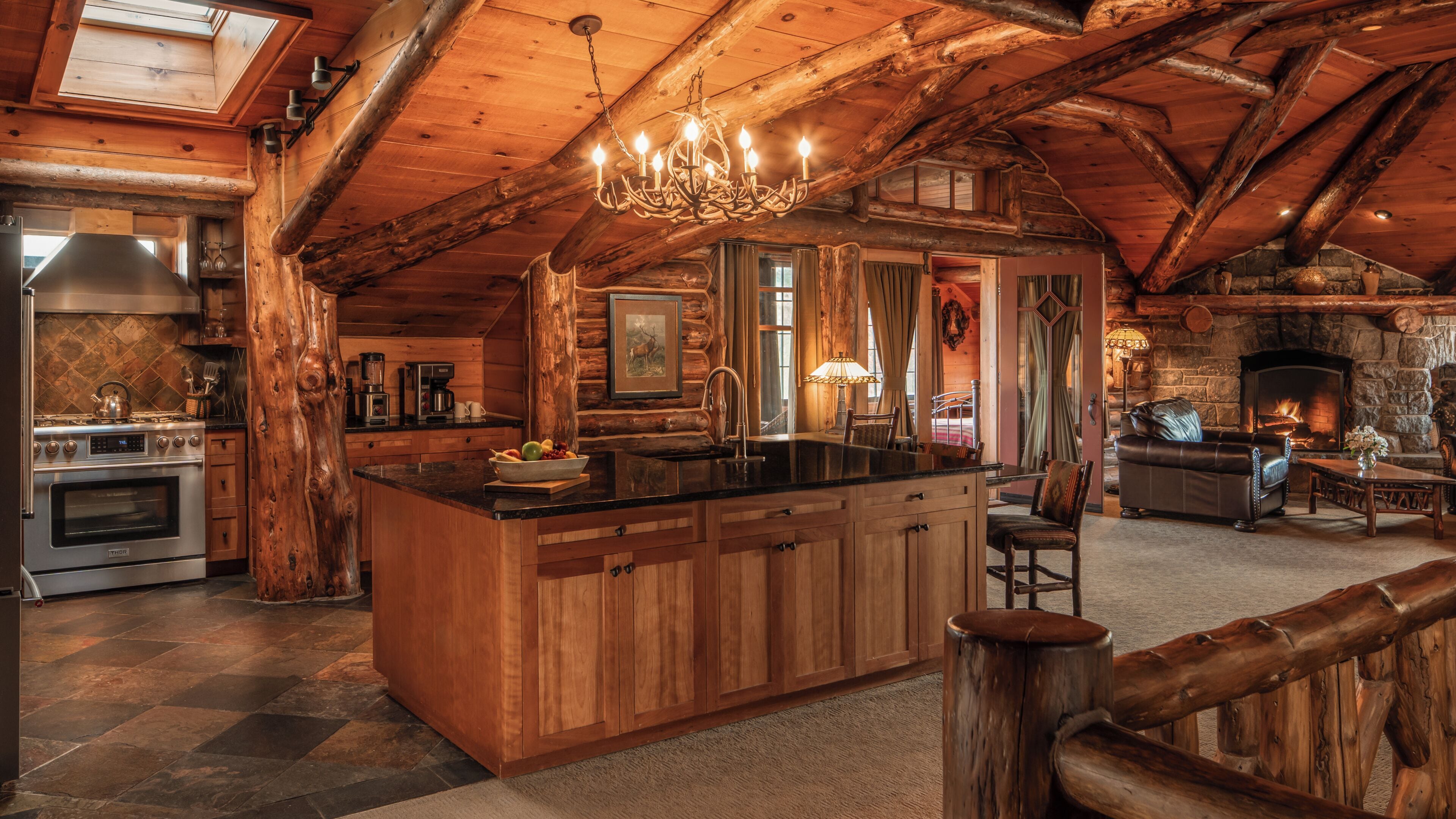 A log cabin interior with a kitchen, dining area, and living room.