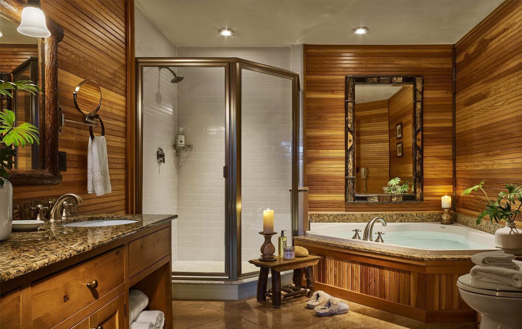 A modern bathroom with a shower, two sinks, a bathtub, and wooden paneling.