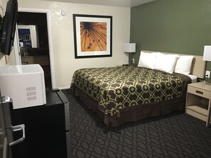 A hotel room with a bed, a desk, a lamp, and a television.