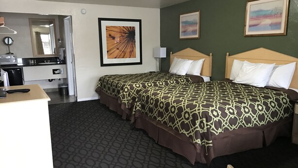 A hotel room with two beds, a desk, a mirror, and artwork on the walls. - Downtown Inn (Eugene)
