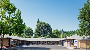 A motel with a row of rooms, a central parking area, and a sign for 'Downtown Inn'. - Downtown Inn (Eugene)