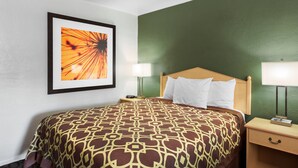 A hotel room with a patterned bedspread, a framed artwork on the wall, and two bedside lamps. - Downtown Inn (Eugene)
