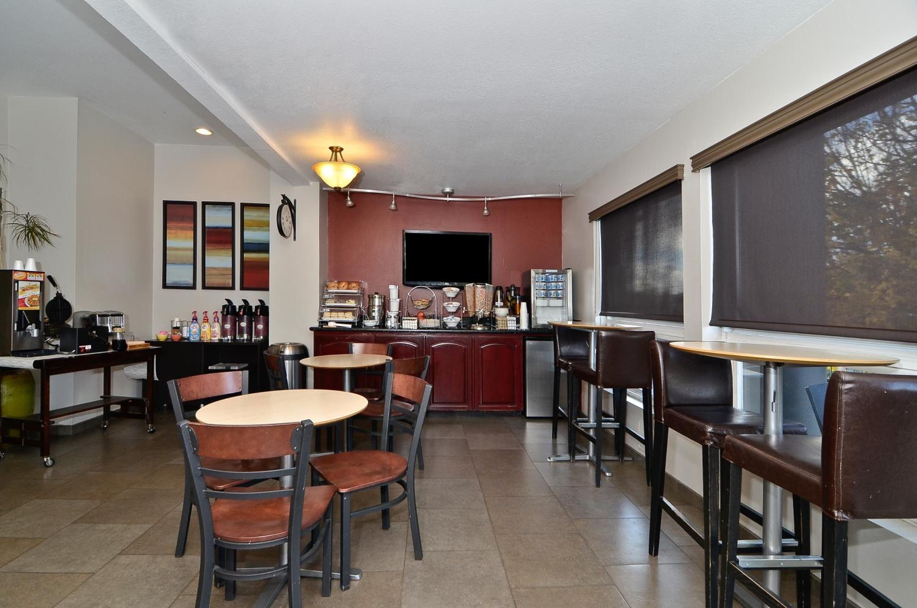 A modern cafe with a bar area, seating, and a television.
