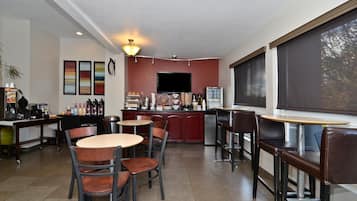 A modern cafe with a bar area, seating, and a television.