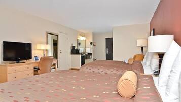 Ein Hotelzimmer mit einem großen Bett, einem Fernseher, einem Schreibtisch und einem Badezimmer.