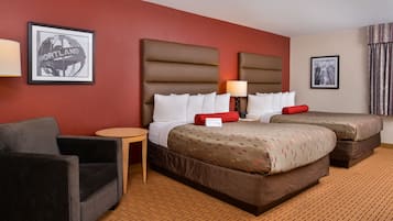 Una habitación de hotel con dos camas, un sofá, una mesita y una lámpara.