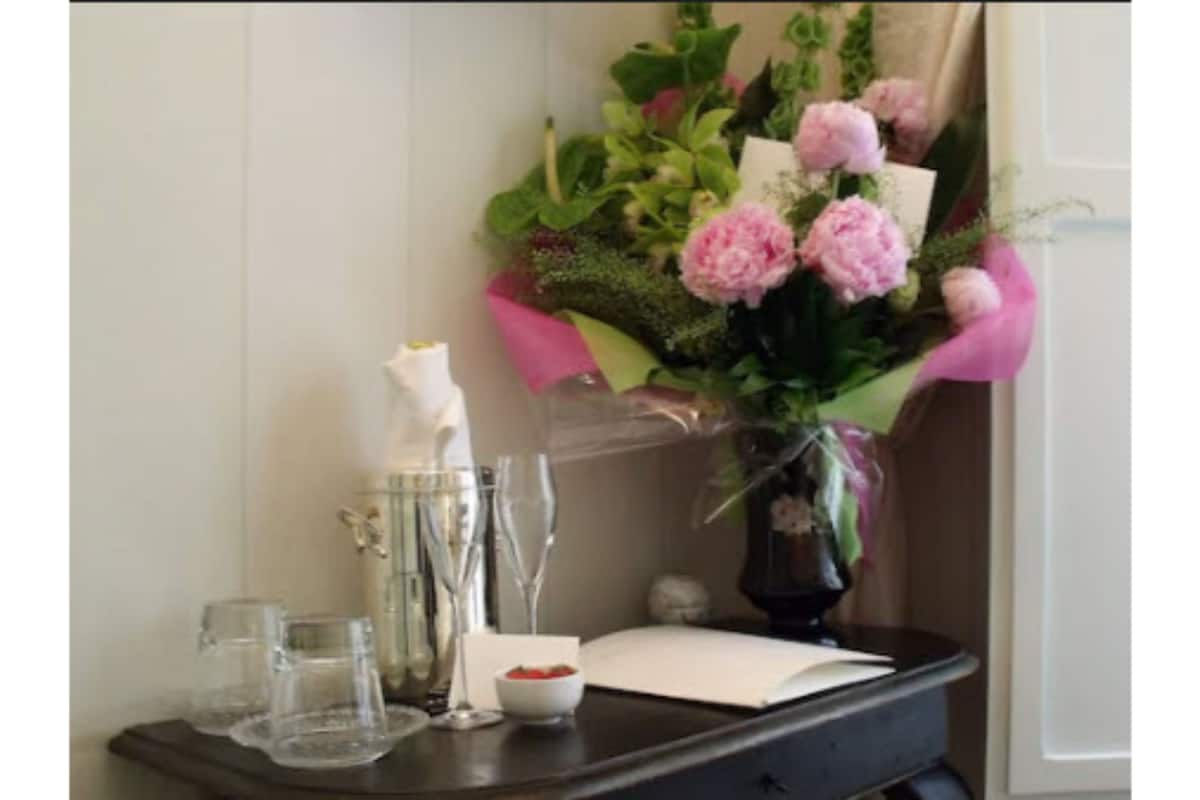 Ein Tisch mit einer Blumenvase, einer weißen Kerze und einer Schale Erdbeeren.