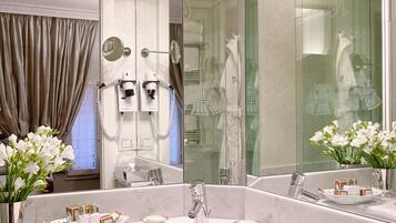 Un baño con un espejo grande, tocador con lavamanos y zona de ducha.