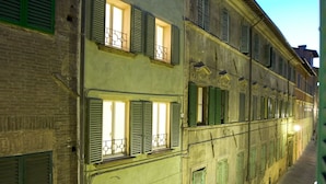 Een smalle straat met historische gebouwen, voorzien van meerdere ramen en balkons, verlicht door straatverlichting.